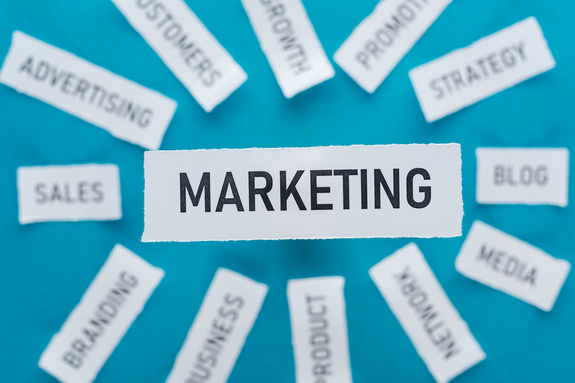 selective focus of word marketing and components related to marketing on pieces of paper on blue selective focus of word marketing and components related to marketing on pieces of paper on blue